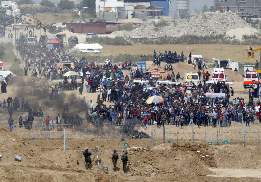 A picture taken on April 13, 2018 from the southern Israeli kibbutz of Nahal Oz across the border with the Gaza Strip shows Israeli soldiers keeping position and Palestinian protestors gathering along the border fence with Israel. Several thousand Gazans gathered for a third consecutive Friday of ma Photo By: JACK GUEZ / AFP Israeli soldiers keeping position and Palestinian protestors gathering along the border fence