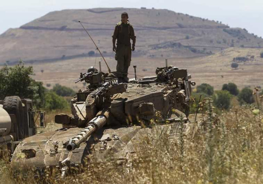 An IDF soldier stands atop a tank near Alonei Habashan on the Golan Heights, close to the ceasefire line between Israel and Syria Photo By: REUTERS An IDF soldier stands atop a tank near Alonei Habashan on the Golan Heights, close to the ceasefire