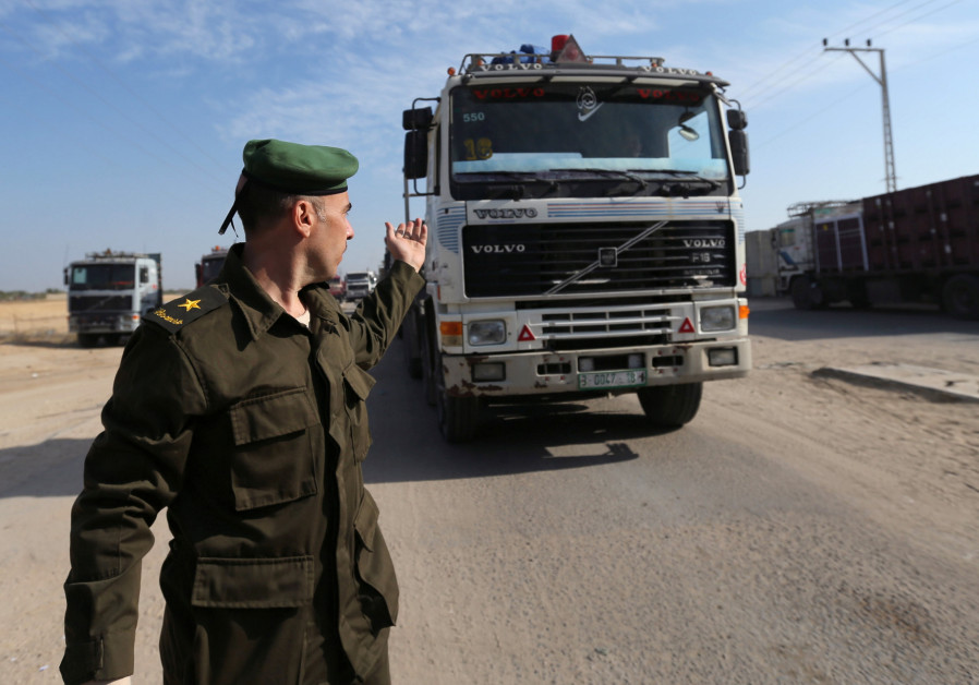 A member of the security forces of the Palestinian Authority gestures as a truck carrying goods arrives at Kerem Shalom crossing in the southern Gaza Strip November 7, 2017. Photo By: REUTERS/IBRAHEEM ABU MUSTAFA Gaza crossing crises: A litmus test for war?
