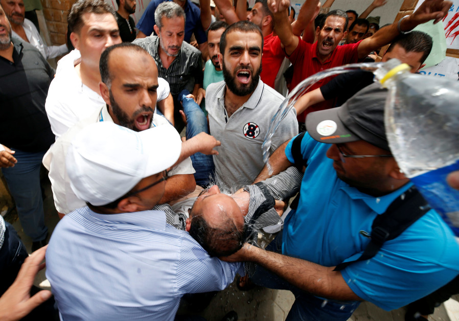 People spray water on a Palestinian UNRWA employee who tried to set himself on fire during a protest against jobs termination by UNRWA inside its headquarters in Gaza City July 25, 2018 Photo By: MOHAMMED SALEM/ REUTERS People spray water on a Palestinian UNRWA employee who tried to set himself on fire