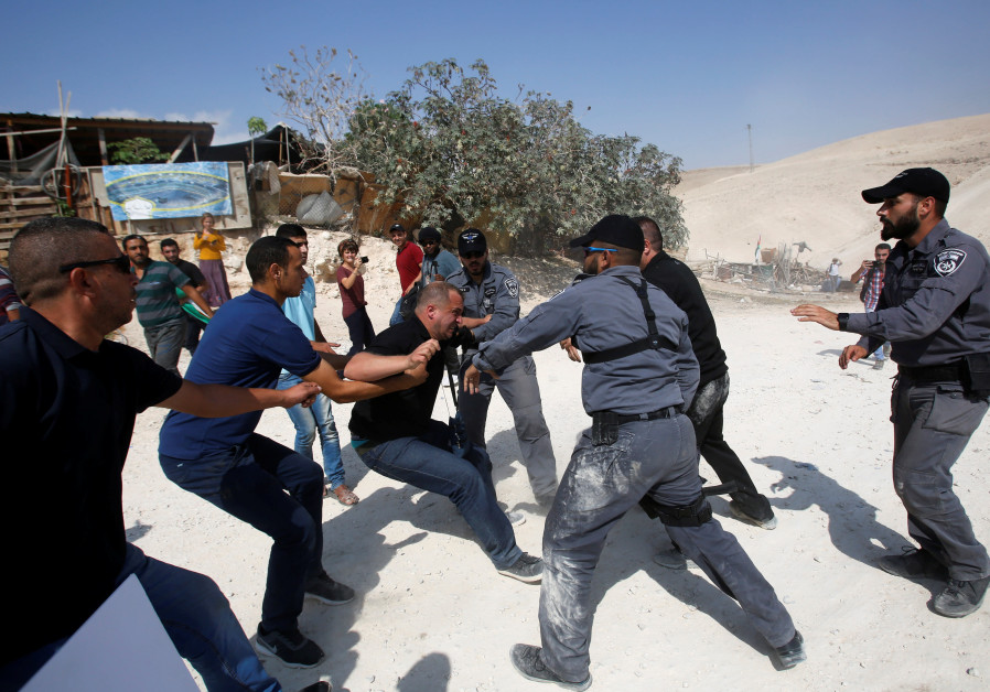 An Israeli policeman grabs an activist in the Palestinian Bedouin village of Khan al-Ahmar in the West Bank October 17, 2018 Photo By: REUTERS/MUSSA QAWASMA An Israeli policeman grabs an activist in the Palestinian Bedouin village of Khan al-Ahmar in the We
