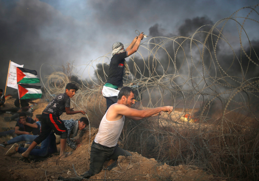 Disable Palestinian tries to remove Israeli wire during a protest at the Israel-Gaza border fence in Gaza. Photo By: MOHAMMED SALEM/ REUTERS Report: Egypt-brokered understanding may end Hamas border violence