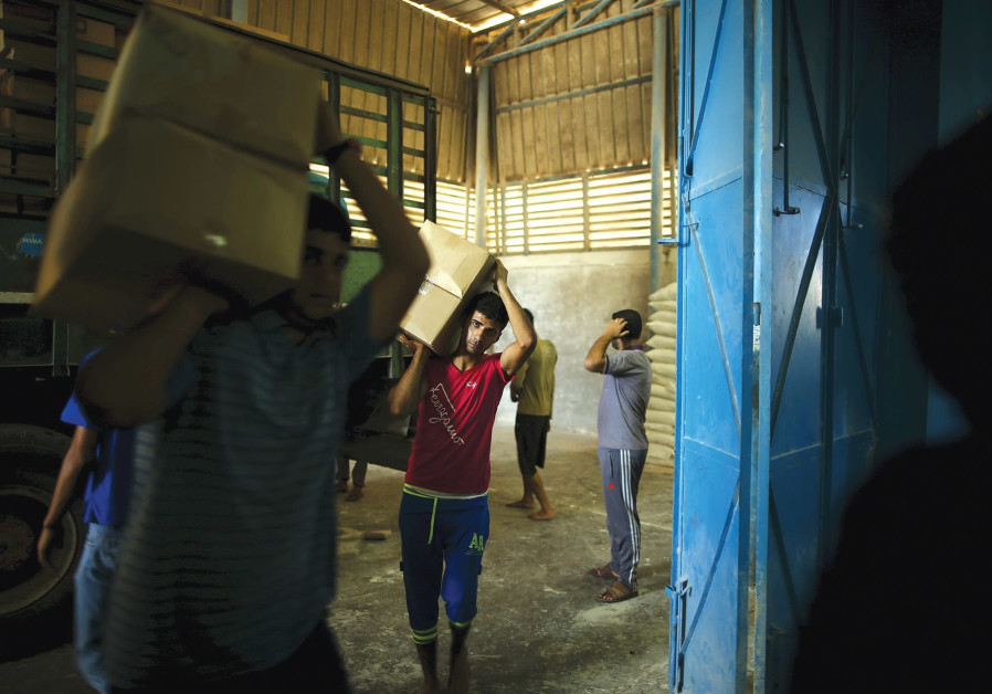 WORKERS CARRY boxes containing food supplies for Palestinian refugees at a United Nations Relief and Work Agency (UNRWA)-run food distribution center in Gaza in 2015. Photo By: MOHAMMED SALEM/ REUTERS WORKERS CARRY boxes containing food supplies for Palestinian refugees at a United Nations Relief and