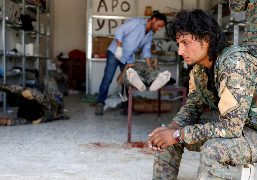 A Syrian Democratic Forces (SDF) fighter sits as medics treat his comrades injured by sniper fired by Islamic State militants in a field hospital in Raqqa, Syria, June 28, 2017. Photo By: GORAN TOMASEVIC/REUTERS A Syrian Democratic Forces (SDF) fighter sits as medics treat his comrades injured by sniper fire