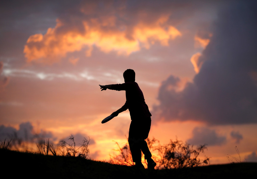 A member of kibbutz plays with his dogs in a field near the border between Israel and Gaza, outside Kibbutz Beeri, Israel, November 16, 2018 Photo By: REUTERS/AMIR COHEN A member of kibbutz plays with his dogs in a field near the border between Israel and Gaza, outside