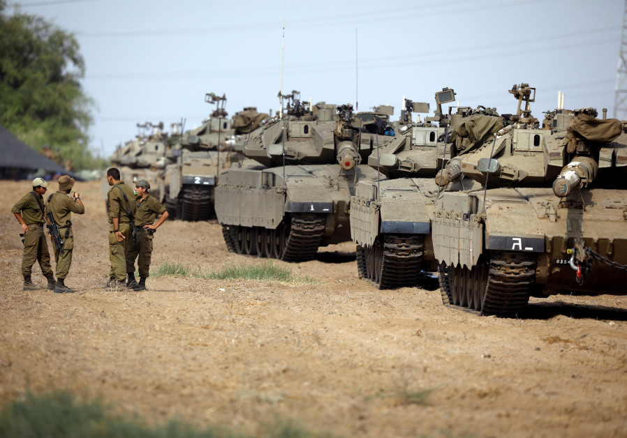 Israeli soldiers speak next to tanks as military armoured vehicles gather in an open area near Israel's border with the Gaza Strip October 18, 2018. Photo By: REUTERS/AMIR COHEN Israeli soldiers speak next to tanks as military armoured vehicles gather in an open area near Israe