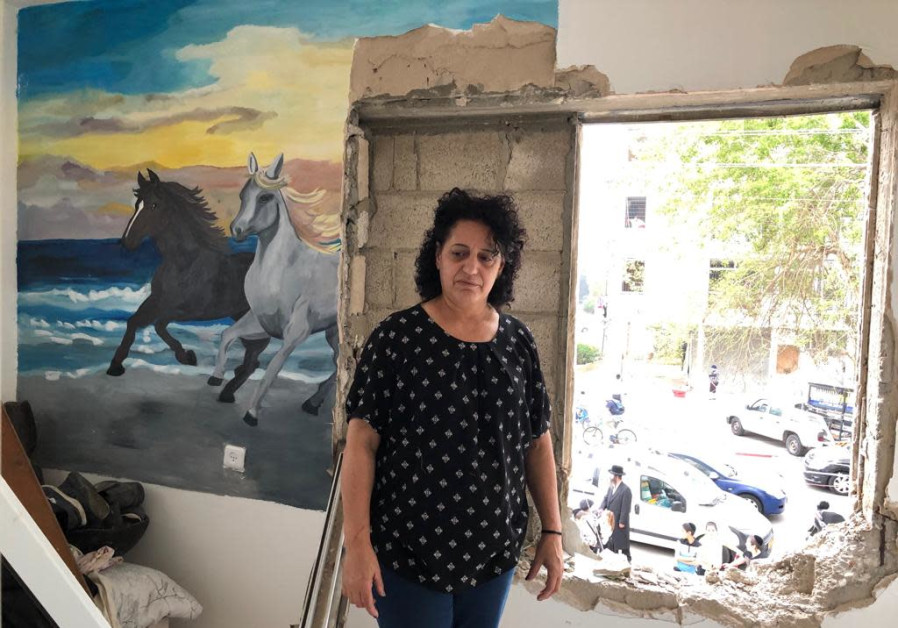 MIRIAM GOTTLIEB stands next to a blown out window and section of a wall in her building, destroyed in Sunday’s rocket attack against Ashdod. Photo By: TOVAH LAZAROFF MIRIAM GOTTLIEB stands next to a blown out window and section of a wall in her building, destroyed i