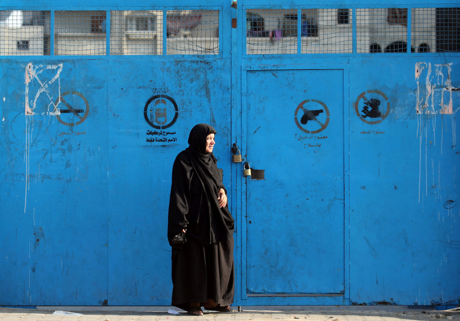 A Palestinian woman stands outside a closed school run by the United Nations Relief and Works Agency (UNRWA), during a strike by the agency's employees union to protest against job cuts, in Khan Younis in the southern Gaza Strip October 2, 2018 Photo By: IBRAHEEM ABU MUSTAFA / REUTERS A Palestinian woman stands outside a closed school run by the United Nations Relief and Works Agency