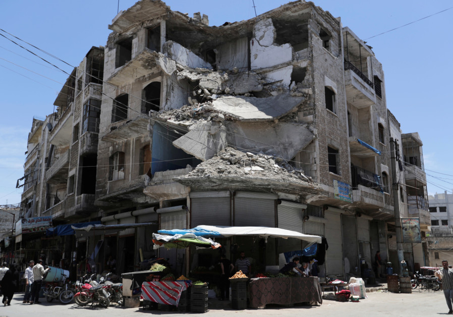 People walk past a damaged building in the city of Idlib on May 31, 2019. Photo By: KHALIL ASHAWI / REUTERS People walk past a damaged building in the city of Idlib on May 31, 2019.