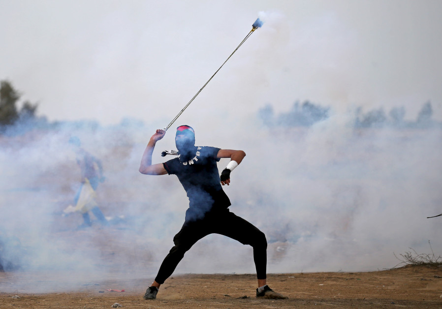 A Palestinian demonstrator uses a sling to hurl back a tear gas canister during an anti-Israel protest at the Israel-Gaza border fence in the southern Gaza Strip October 25, 2019 Photo By: REUTERS/IBRAHEEM ABU MUSTAFA 88 injured in weekly Great Return March riot
