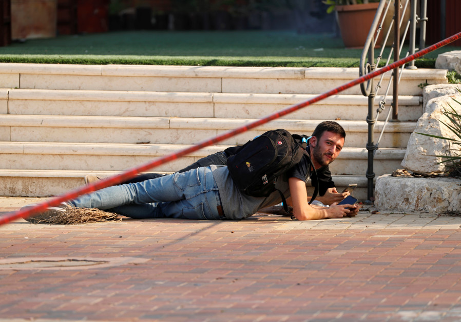 Israelis take cover as a siren warning of incoming rockets sounds in Sderot Photo By: REUTERS Israelis take cover as a siren warning of incoming rockets sounds in Sderot