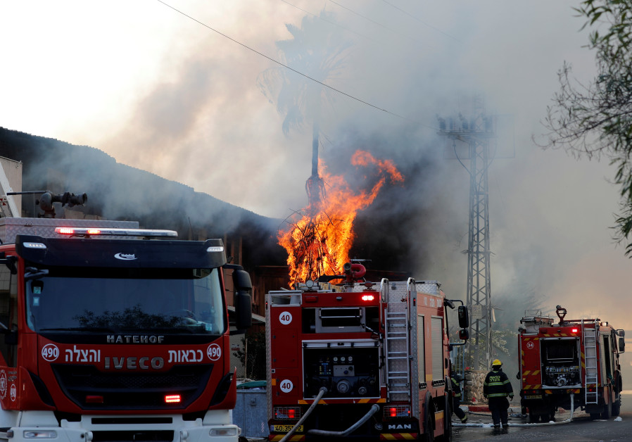 Israeli firefighters work to extinguish a blazing tree after a factory caught on fire in Sderot Photo By: REUTERS Israeli firefighters work to extinguish a blazing tree after a factory caught on fire in Sderot