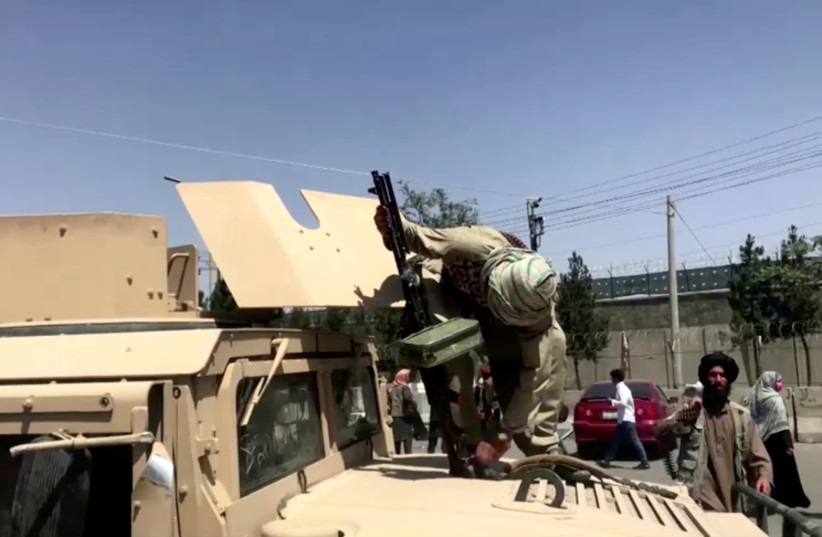 A Taliban fighter on top of an armoured vehicle loads a gun outside the airport in Kabul, Afghanistan August 16, 2021, in this still image taken from a video. (credit: REUTERS TV/via REUTERS) A Taliban fighter on top of an armoured vehicle loads a gun outside the airport in Kabul, Afghanistan August 16, 2021, in this still image taken from a video. (credit: REUTERS TV/via REUTERS)