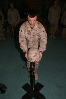 Sean Paul places a helmet on a battlefield cross during a memorial service for a Marine his unit lost in 2006 in Fallujah. Photo courtesy of the author.