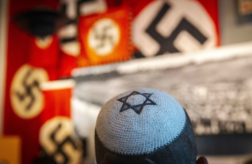 Visitors seen standing next to a display of swastika banners at the Yad Vashem Holocaust Memorial museum in Jerusalem on April 26, 2022, ahead of Israeli Holocaust Remembrance Day. (credit: OLIVIER FITOUSSI/FLASH90) Visitors seen standing next to a display of swastika banners at the Yad Vashem Holocaust Memorial museum in Jerusalem on April 26, 2022, ahead of Israeli Holocaust Remembrance Day. (credit: OLIVIER FITOUSSI/FLASH90)
