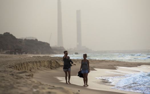 Tourists walk at the shore of the Mediterranean sea in Ashkelon in southern Israel during heavy hazy weather in the region (credit: REUTERS) Tourists walk at the shore of the Mediterranean sea in Ashkelon in southern Israel during heavy hazy weather in the region (credit: REUTERS)