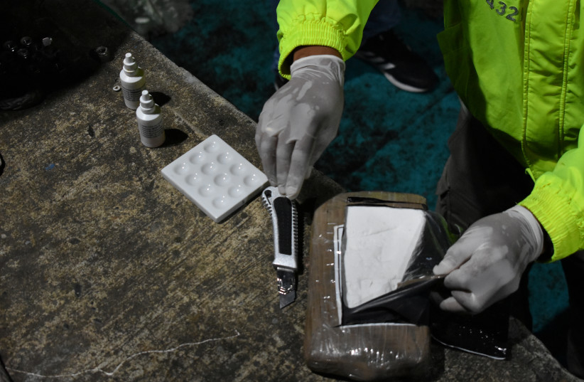 A police officer opens a cocaine hydrochloride package during the seizure of a semi-submersible sea vessel loaded with more than a ton of cocaine hydrochloride in Tumaco, Colombia August 23, 2020 (credit: VIA REUTERS) A police officer opens a cocaine hydrochloride package during the seizure of a semi-submersible sea vessel loaded with more than a ton of cocaine hydrochloride in Tumaco, Colombia August 23, 2020 (credit: VIA REUTERS)