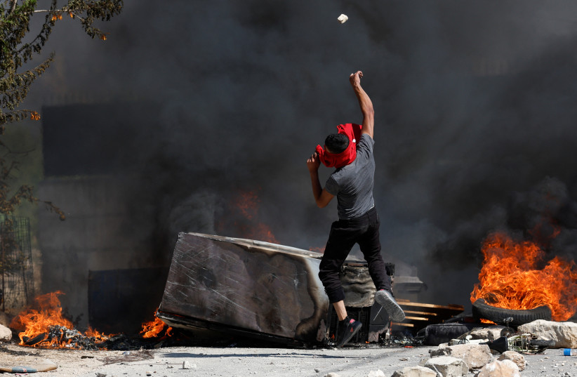 A Palestinian throws a stone during clashes with Israeli troops after Israeli settlers attack Umm Safa village near Ramallah, in the West Bank, June 24, 2023 (credit: REUTERS/MOHAMAD TOROKMAN) A Palestinian throws a stone during clashes with Israeli troops after Israeli settlers attack Umm Safa village near Ramallah, in the West Bank, June 24, 2023 (credit: REUTERS/MOHAMAD TOROKMAN)