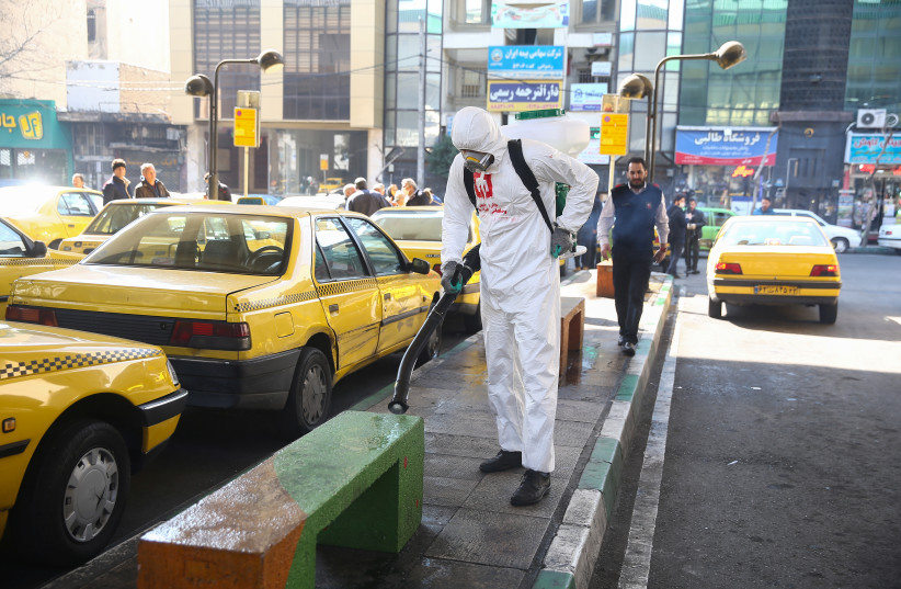 A member of the medical team wears a protective face mask, following the coronavirus outbreak, as he sprays disinfectant liquid to sanitise a taxi station in Tehran, Iran March 05, 2020 (credit: WANA (WEST ASIA NEWS AGENCY)/NAZANIN TABATABAEE VIA REUTERS) A member of the medical team wears a protective face mask, following the coronavirus outbreak, as he sprays disinfectant liquid to sanitise a taxi station in Tehran, Iran March 05, 2020 (credit: WANA (WEST ASIA NEWS AGENCY)/NAZANIN TABATABAEE VIA REUTERS)