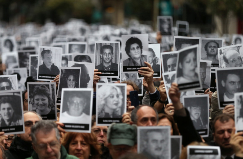 HOLDING UP images of the victims of the 1994 bombing on Argentina’s AMIA center, to mark the attack’s 25th anniversary, in Buenos Aires, July 18, 2019. (credit: AGUSTIN MARCARIAN/REUTERS) HOLDING UP images of the victims of the 1994 bombing on Argentina’s AMIA center, to mark the attack’s 25th anniversary, in Buenos Aires, July 18, 2019. (credit: AGUSTIN MARCARIAN/REUTERS)