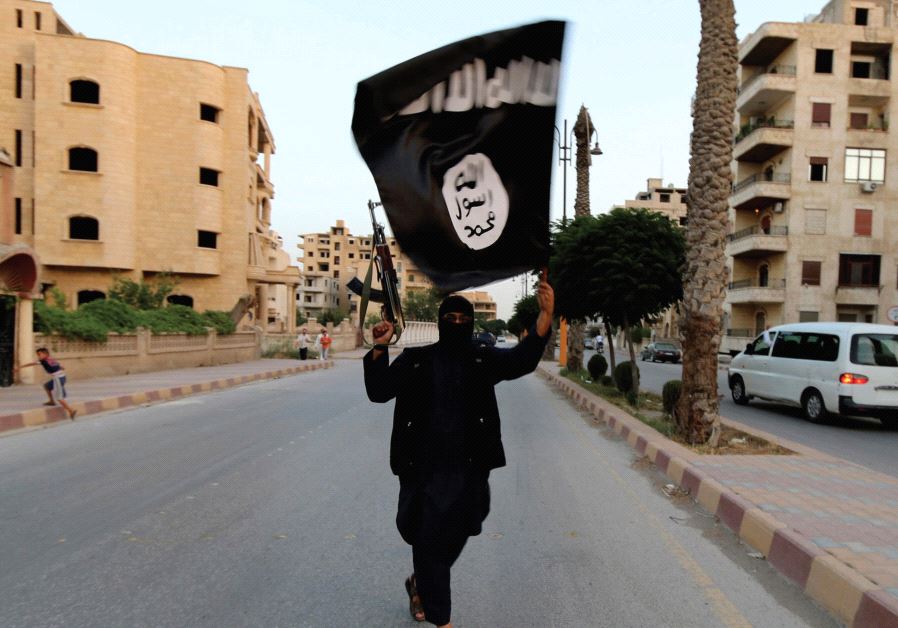 A MEMBER of ISIS waves the group’s flag in Raqqa (credit: REUTERS) A MEMBER of ISIS waves the group’s flag in Raqqa (credit: REUTERS)
