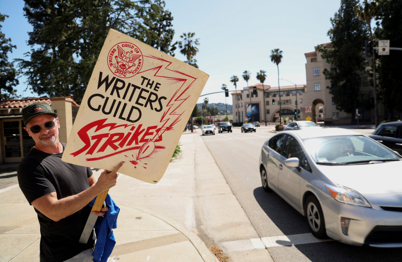 Board member of the Writers Guild of America (WGA) Dante Harper holds a protest sign that was used during the first WGA strike, in Burbank, California, US, May 2, 2023. (credit: MARIO ANZUONI/REUTERS) Board member of the Writers Guild of America (WGA) Dante Harper holds a protest sign that was used during the first WGA strike, in Burbank, California, US, May 2, 2023. (credit: MARIO ANZUONI/REUTERS)