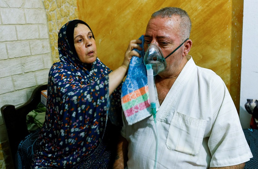 Aisha Nashwan helps her husband Ismail Nashwan at their house amid a heatwave in Al Burij refugee camp, central Gaza Strip, August 9, 2023. (credit: IBRAHEEM ABU MUSTAFA/REUTERS) Aisha Nashwan helps her husband Ismail Nashwan at their house amid a heatwave in Al Burij refugee camp, central Gaza Strip, August 9, 2023. (credit: IBRAHEEM ABU MUSTAFA/REUTERS)