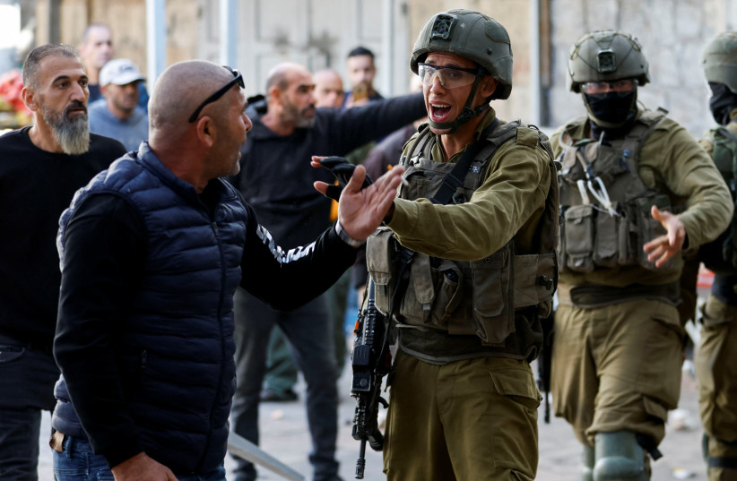 An Israeli soldier gestures during a scuffle between Palestinians and Israeli settlers in Hebron in the West Bank November 19, 2022. (credit: MUSSA QAWASMA/REUTERS) An Israeli soldier gestures during a scuffle between Palestinians and Israeli settlers in Hebron in the West Bank November 19, 2022. (credit: MUSSA QAWASMA/REUTERS)