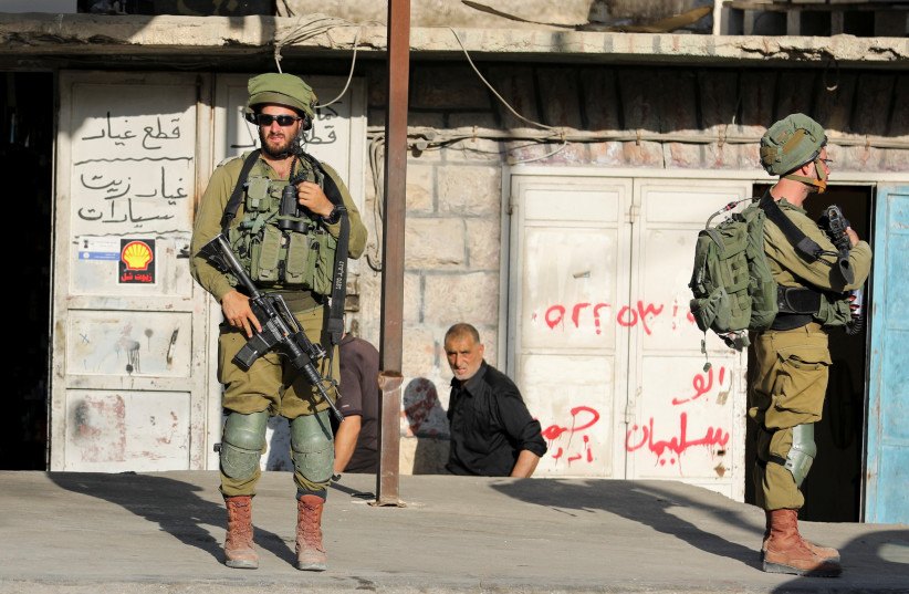 Israeli soldiers stand while stationed outside a Palestinian shop in Huwara, Israeli-occupied West Bank, May 26, 2022. (credit: RANEEN SAWAFTA/ REUTERS) Israeli soldiers stand while stationed outside a Palestinian shop in Huwara, Israeli-occupied West Bank, May 26, 2022. (credit: RANEEN SAWAFTA/ REUTERS)