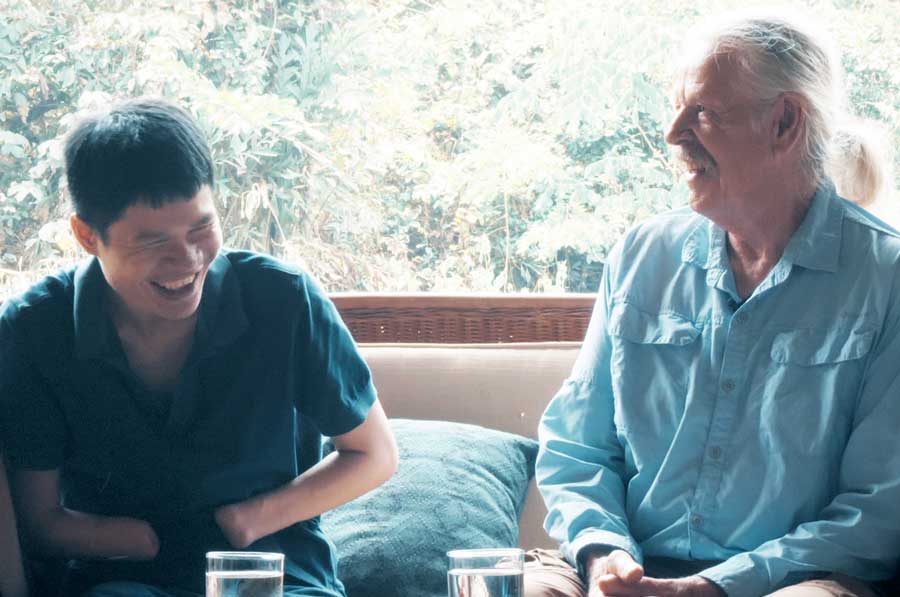 Don Super chats with Phongsavath “Pong” Manithong, one of the many who have been severely injured by a blast from a mine. (Photo courtesy of Ken Hayes and the documentary film Collateral Damage)