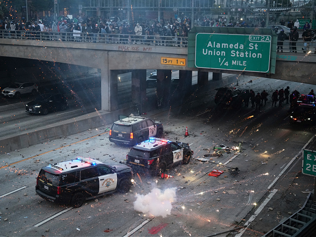 EDS NOTE: OBSCENITY A flash bomb explodes on the 101 Freeway near the metropolitan detention center of downtown Los Angeles, Sunday, June 8, 2025, following last night's immigration raid protest. (AP Photo/Eric Thayer)